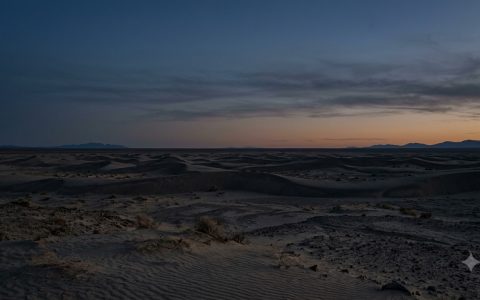 Cinematic wide shot of a vast, desolate desert landscape under a twilight sky, deep silence, emptiness, desaturated colors, natural lighting, high res