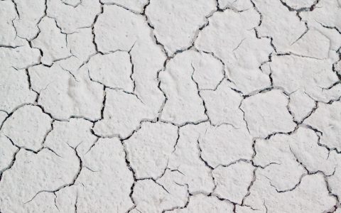 Close-up of a hairline crack on the surface of a white acrylic bathtub