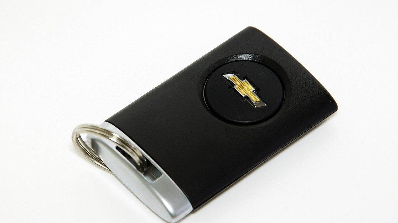 Modern automotive smart key fobs and a diagnostic scanning tool arranged on a workbench.