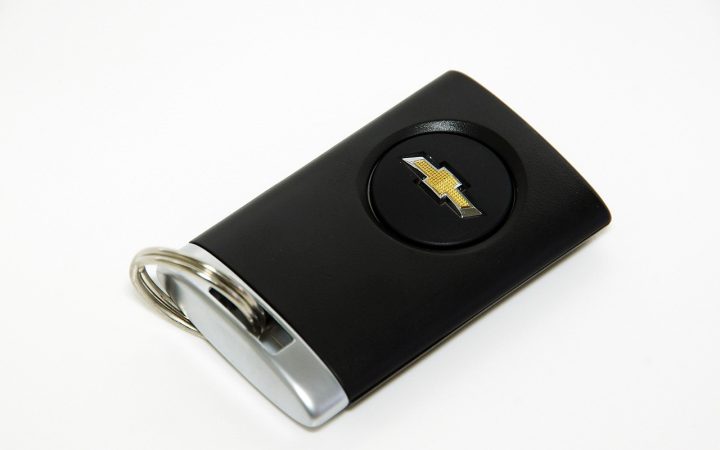Modern automotive smart key fobs and a diagnostic scanning tool arranged on a workbench.