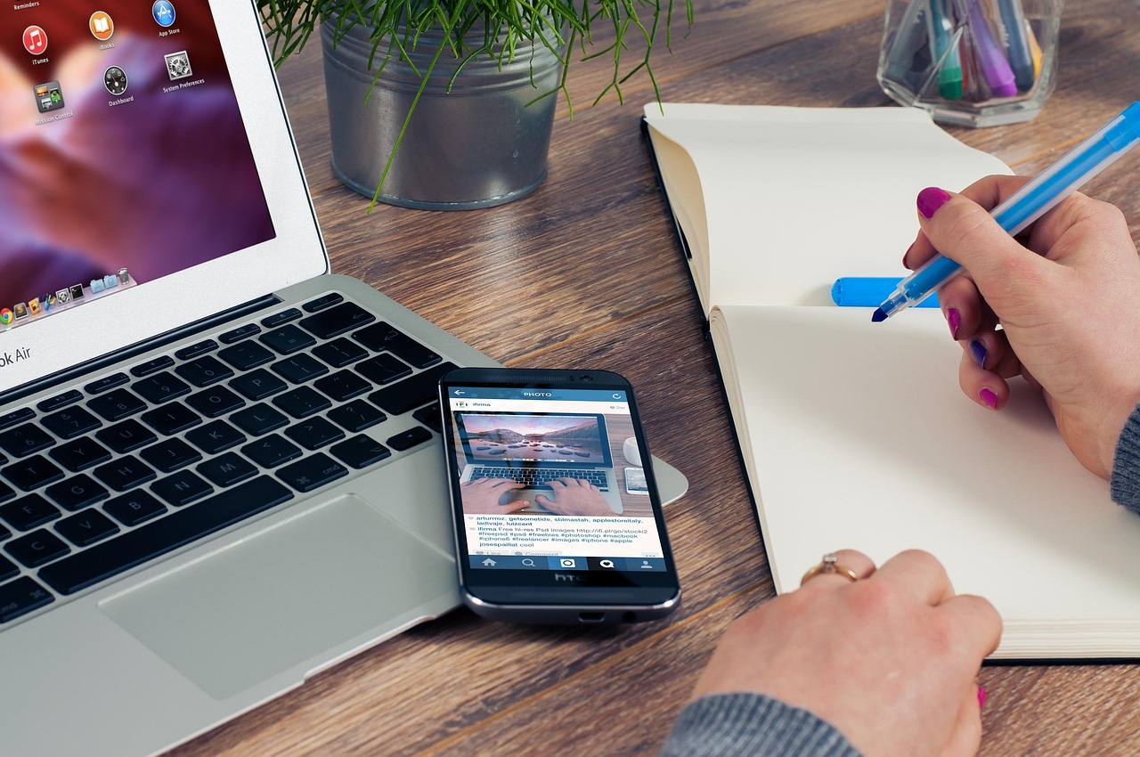 Hands managing financial notes and digital records on a wooden office desk next to a laptop.