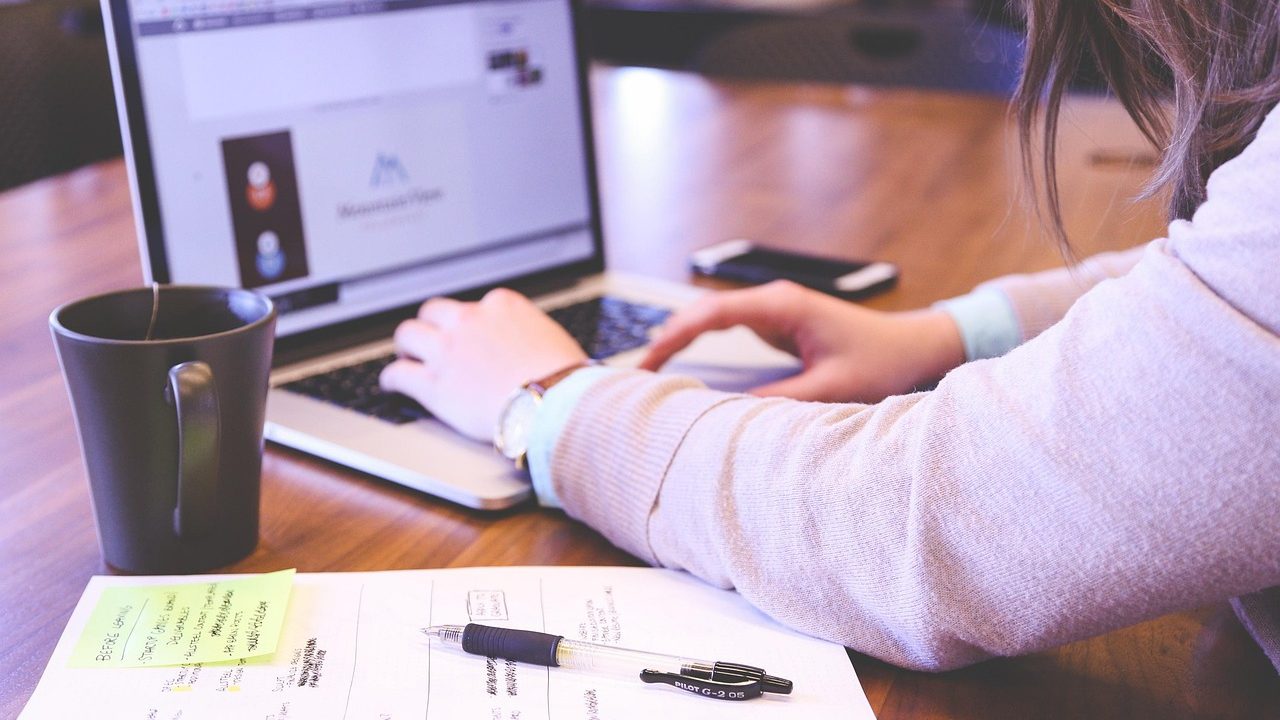 A small business owner managing digital workflows on a monitor in a bright office.