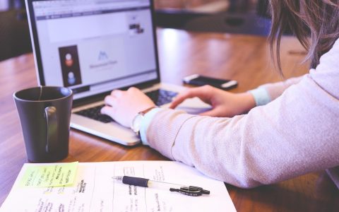 A small business owner managing digital workflows on a monitor in a bright office.