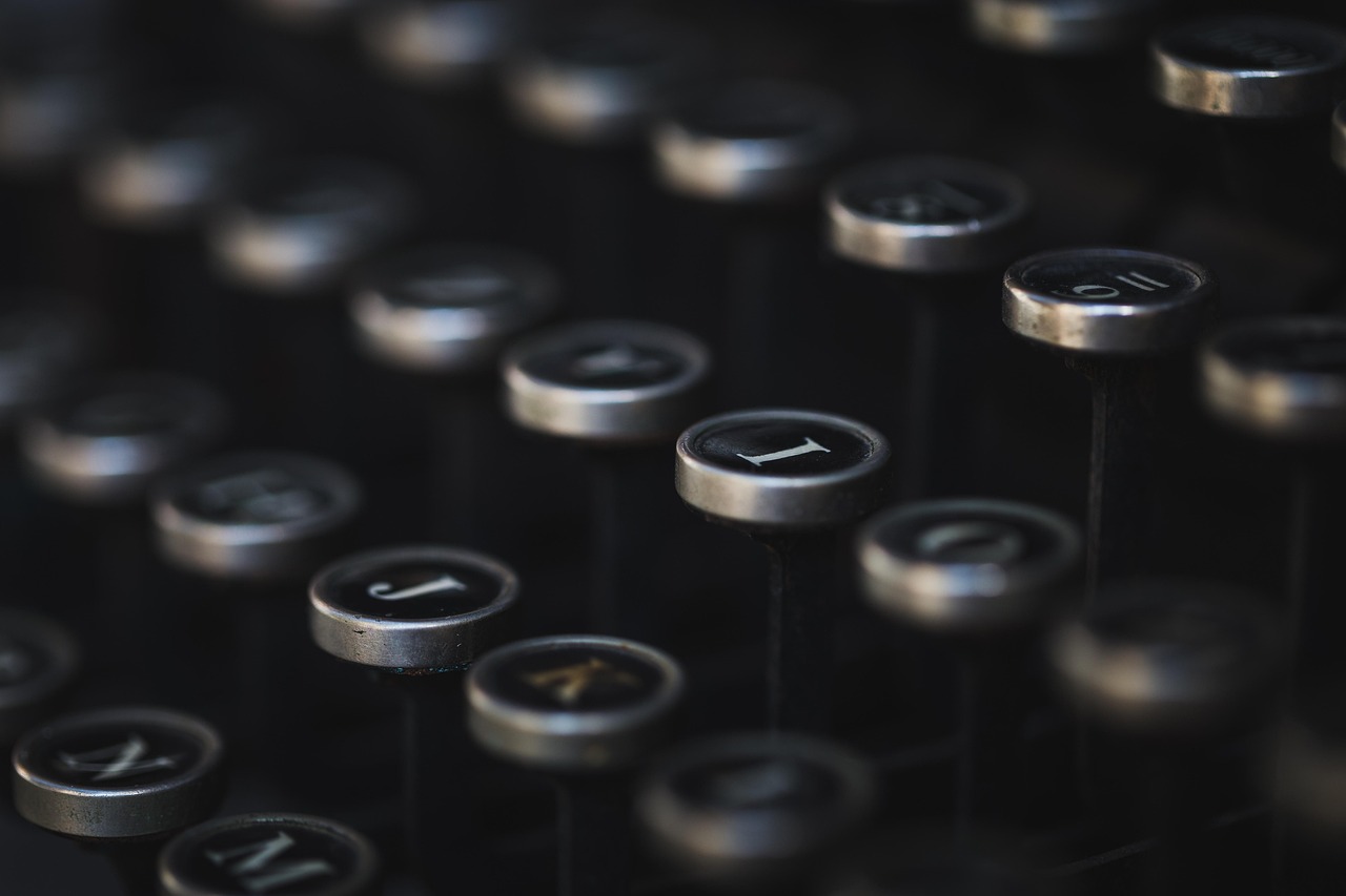 Close-up of hands typing on a keyboard beside a notebook in a modern office.