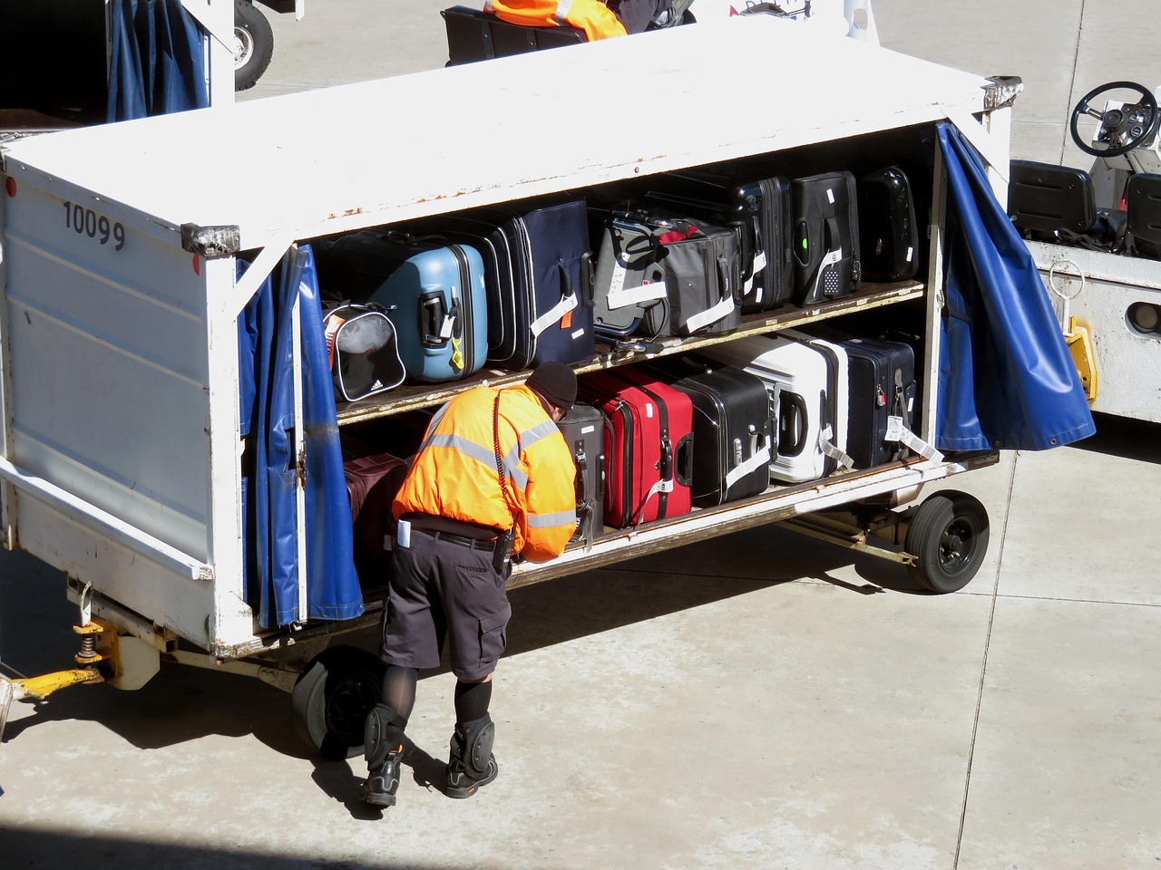 Carry-on baggage placed next to an airline luggage sizer frame at an airport check-in desk.