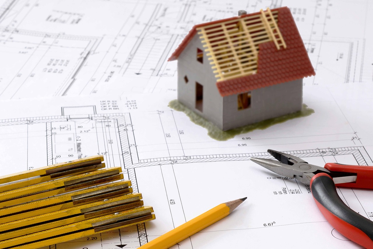 Architect and contractor reviewing blueprint documents inside a framed house under construction.