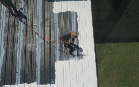 Contractors installing metal roofing panels on a residential home