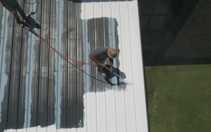Contractors installing metal roofing panels on a residential home