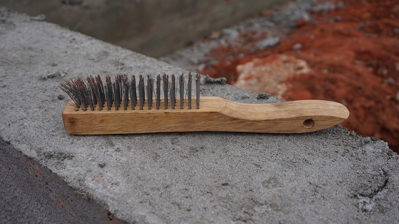 Using a wire brush to clean debris out of an asphalt crack