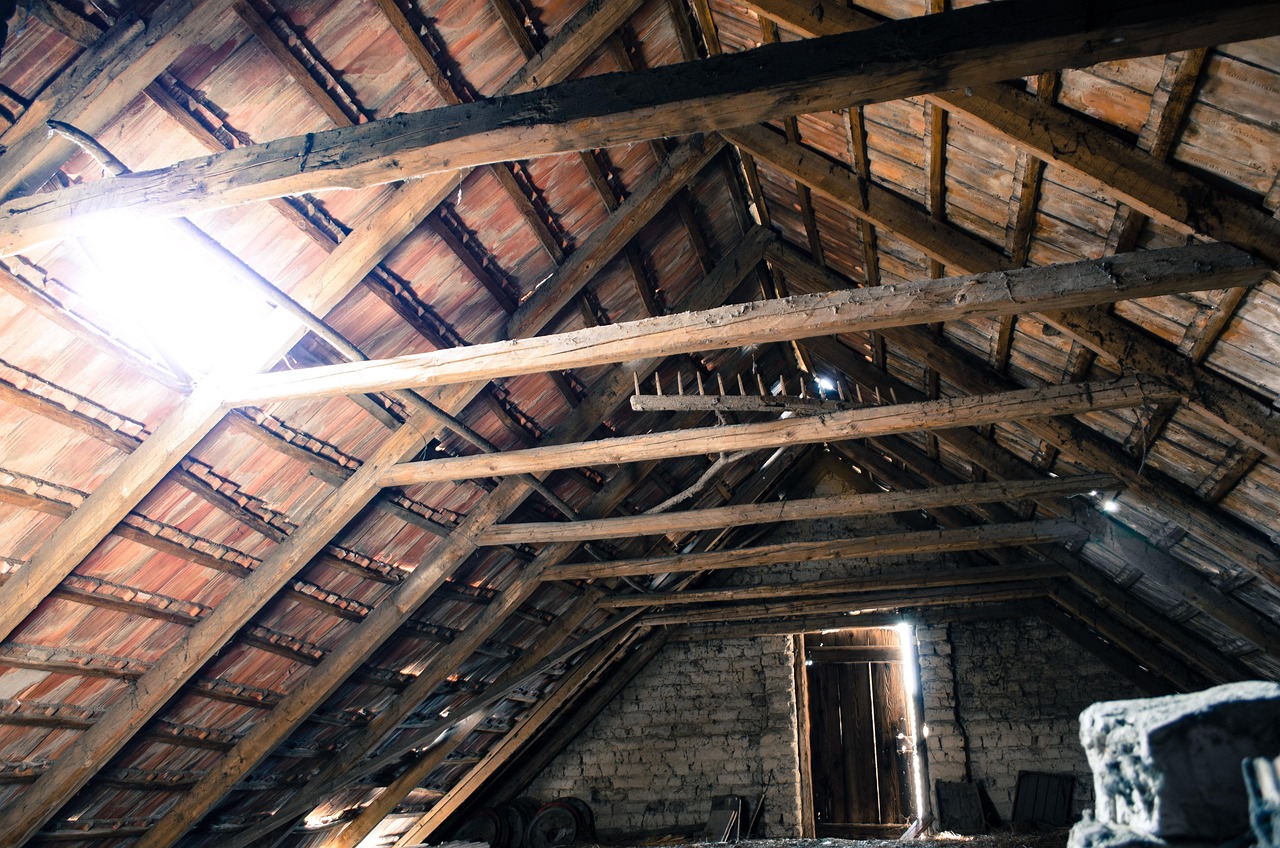 A zippered reflective attic stair insulation tent installed over fold-down stairs inside an attic.
