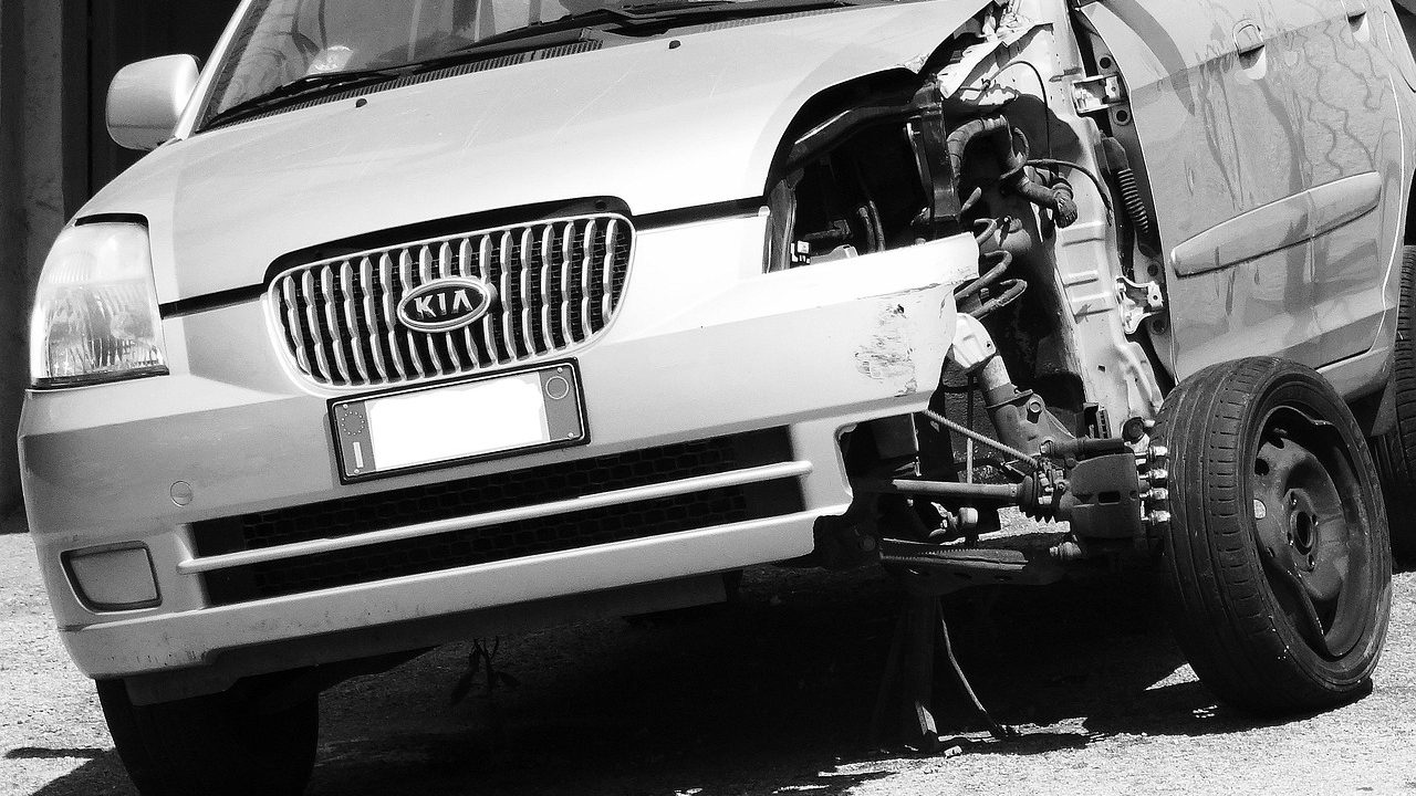 A midsize rental vehicle parked outside a professional automobile collision repair garage.
