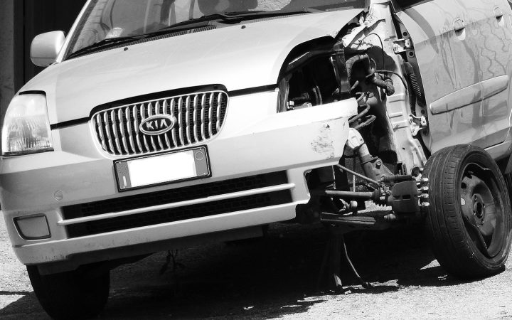 A midsize rental vehicle parked outside a professional automobile collision repair garage.