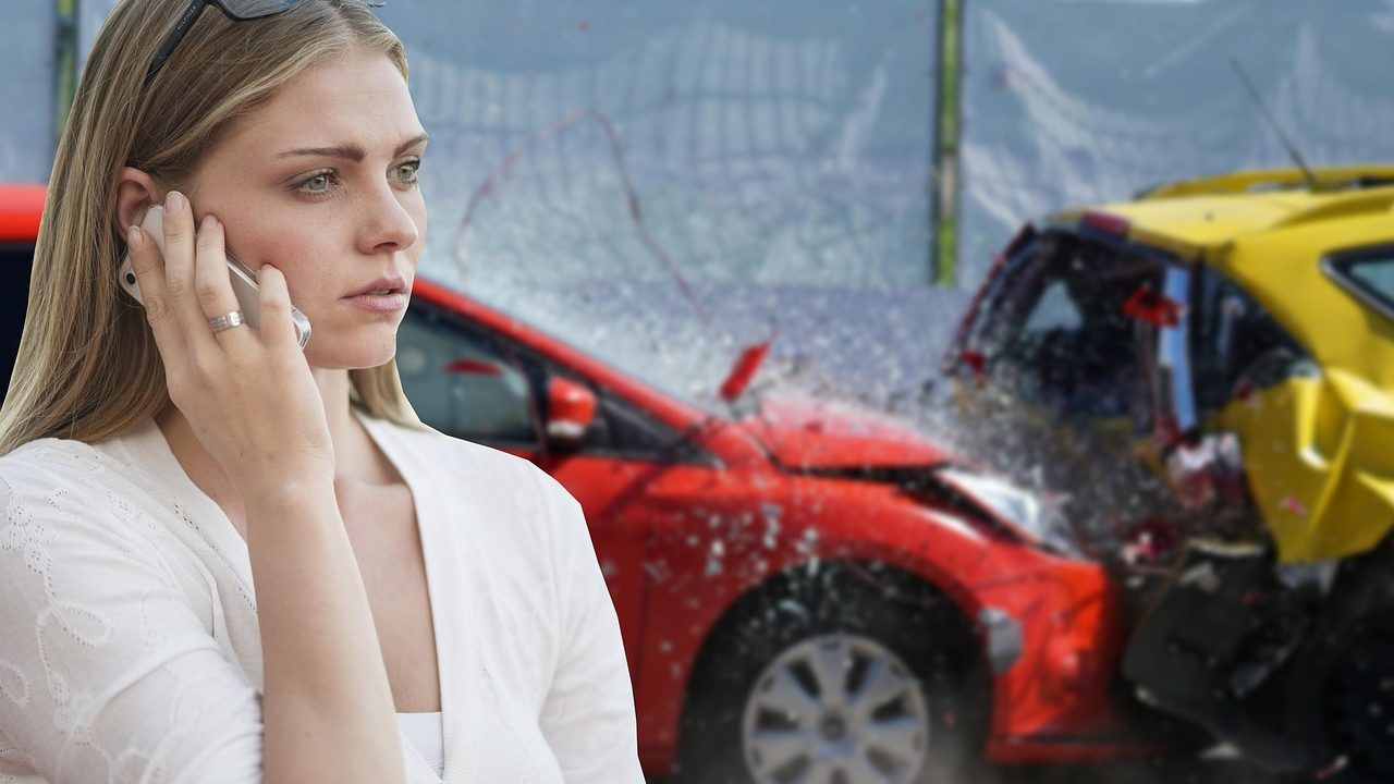 An insurance adjuster examining a damaged vehicle in an outdoor tow lot.