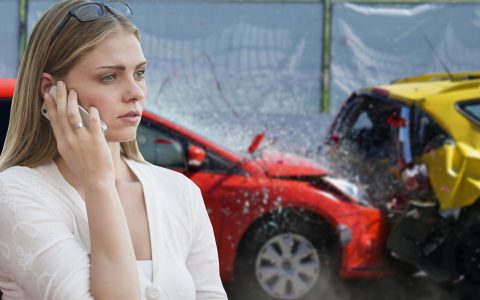 An insurance adjuster examining a damaged vehicle in an outdoor tow lot.
