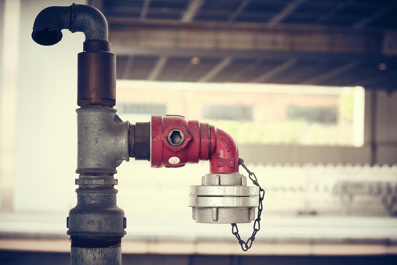 Outdoor backflow preventer assembly wrapped in thick foam insulation for winter freeze protection.