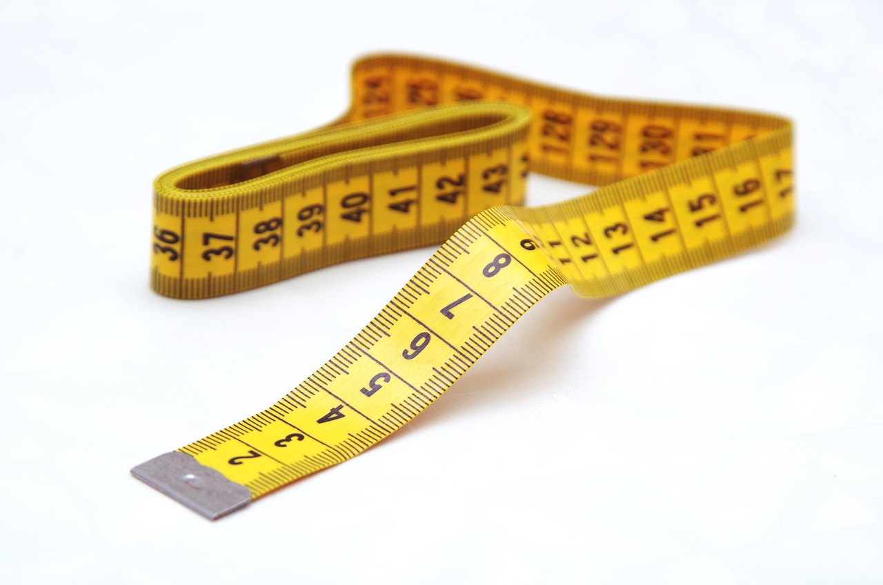 Hands using a metal tape measure to size a small basement window opening