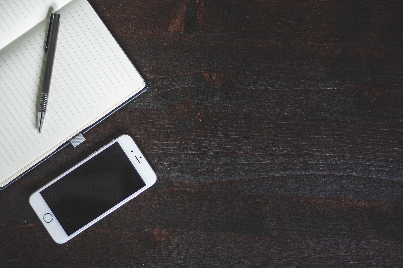 Automated banking app notification on a phone resting on an organized desk.