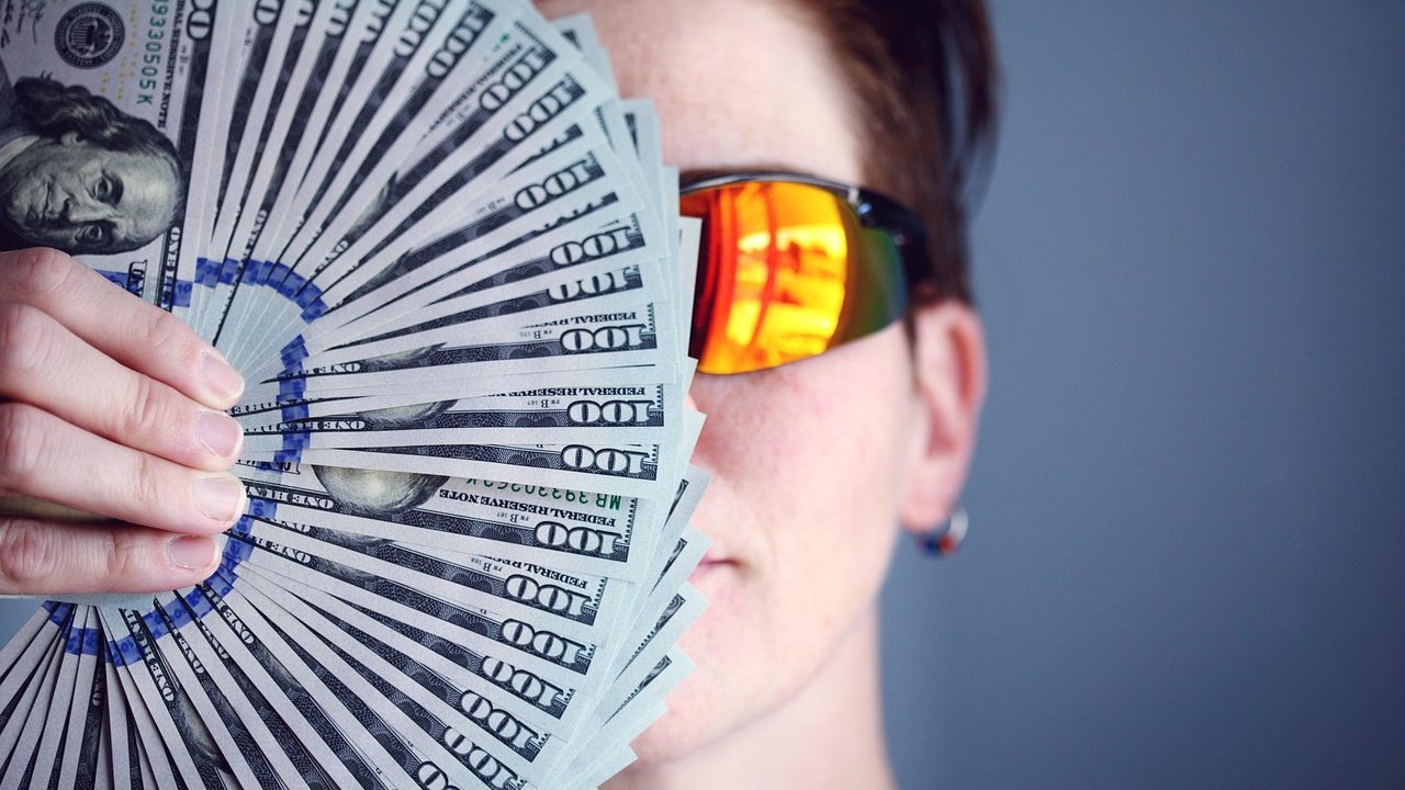 An investor quietly reviewing paper financial records at a sunny home office desk.