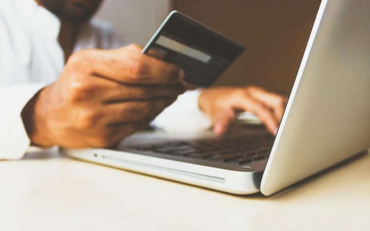 Laptop open on a clean desk displaying charts next to a credit card and coffee cup.