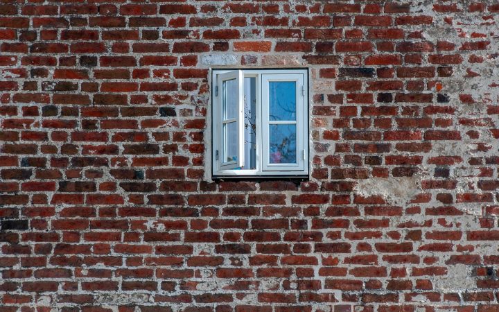 Insulation contractor retrofitting exterior house wall cavity with blown-in insulation