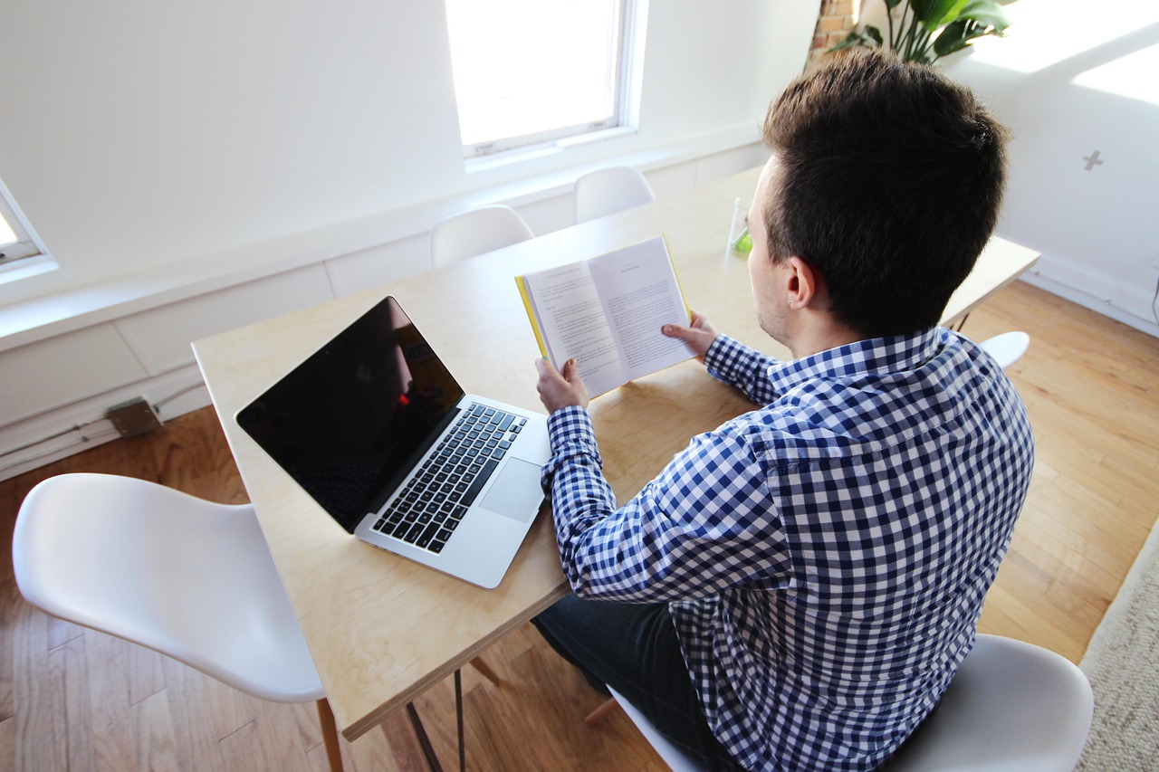 A mid-career professional reviewing documents on a laptop in a corporate office.