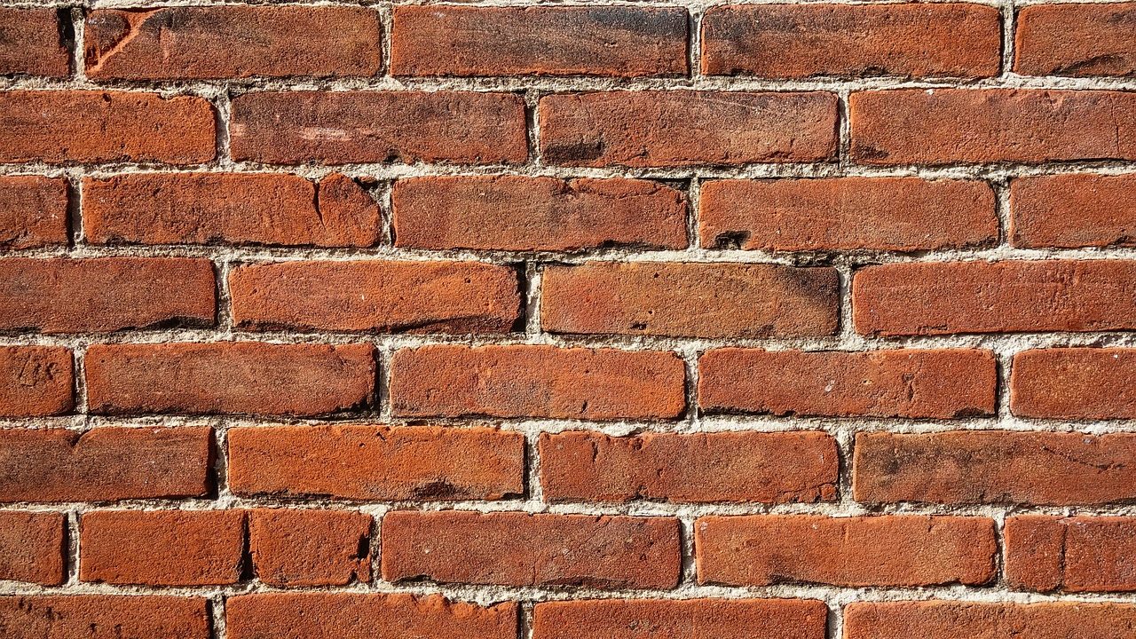 Mason repairing exterior brick mortar joint with a tuckpointing trowel