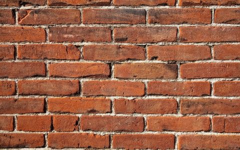 Mason repairing exterior brick mortar joint with a tuckpointing trowel