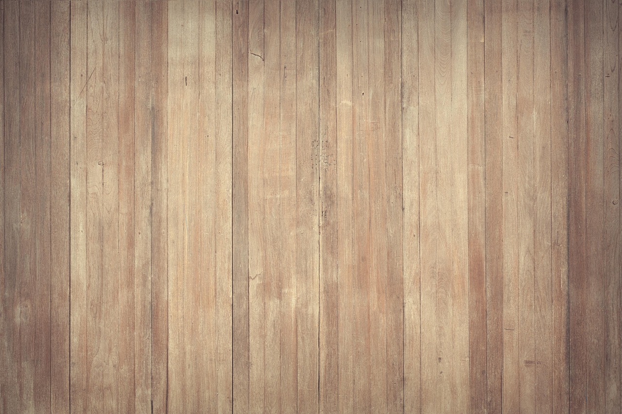 Person using a cordless stick vacuum on a hardwood living room floor.