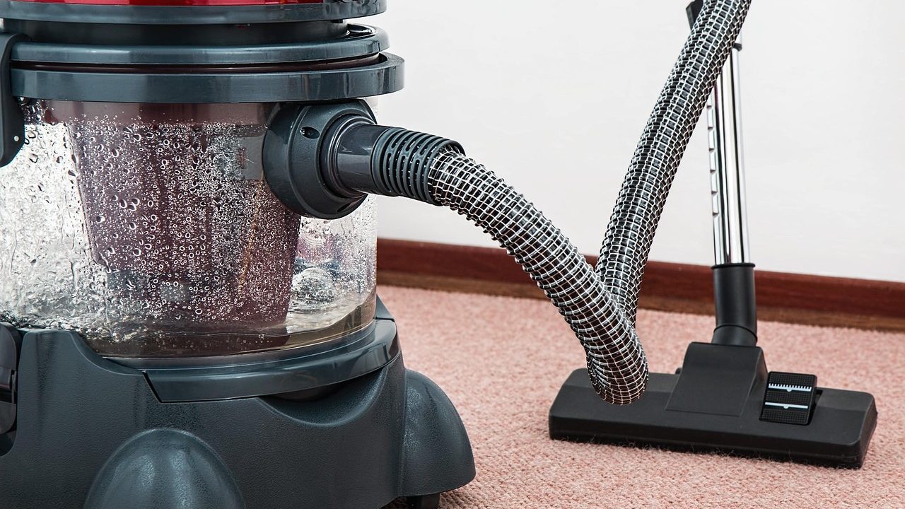 Close-up of a person inspecting and cleaning a cordless stick vacuum filter and floor head.