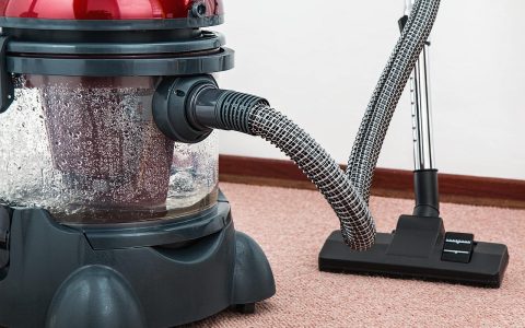 Close-up of a person inspecting and cleaning a cordless stick vacuum filter and floor head.