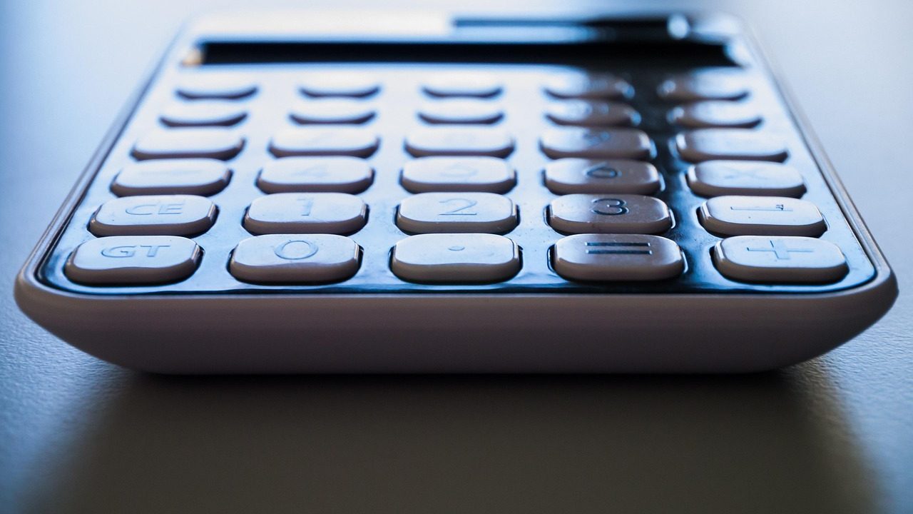 Close-up of a paper utility statement and calculator on a wooden desk.