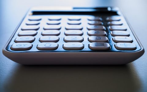 Close-up of a paper utility statement and calculator on a wooden desk.