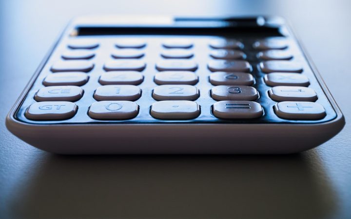 Close-up of a paper utility statement and calculator on a wooden desk.