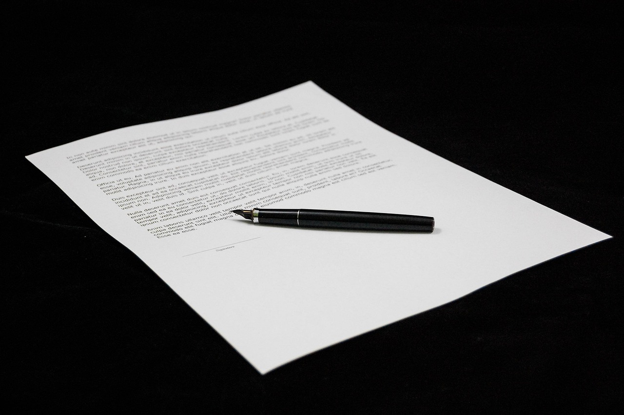 An auto lease agreement document on a wooden table beside a car key fob and a digital calculator.