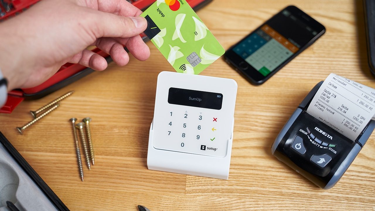 A consumer making a card payment at a modern retail checkout terminal.