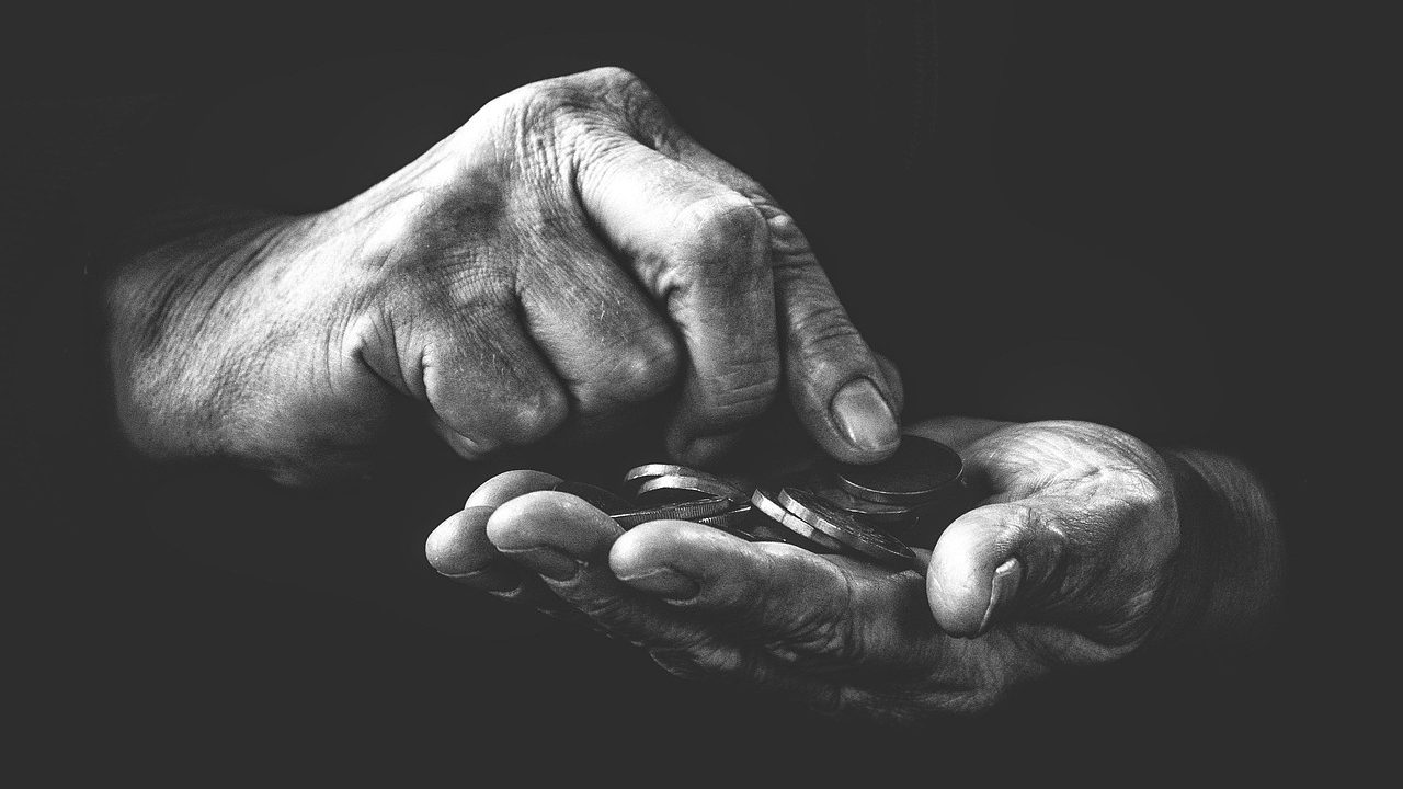 Parent and child sitting at a kitchen table counting dollar bills and coins together.