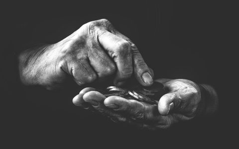 Parent and child sitting at a kitchen table counting dollar bills and coins together.
