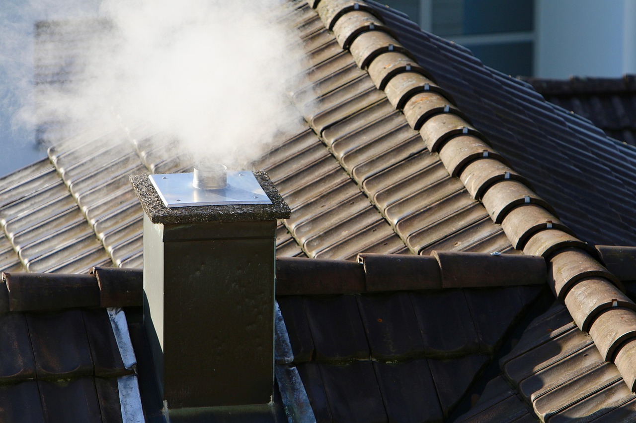 Mason working on rebuilding a brick chimney top above the roofline.