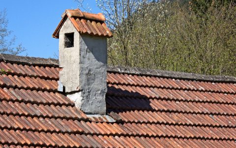 Close-up of a brick chimney on an asphalt shingle roof with custom copper counter-flashing.