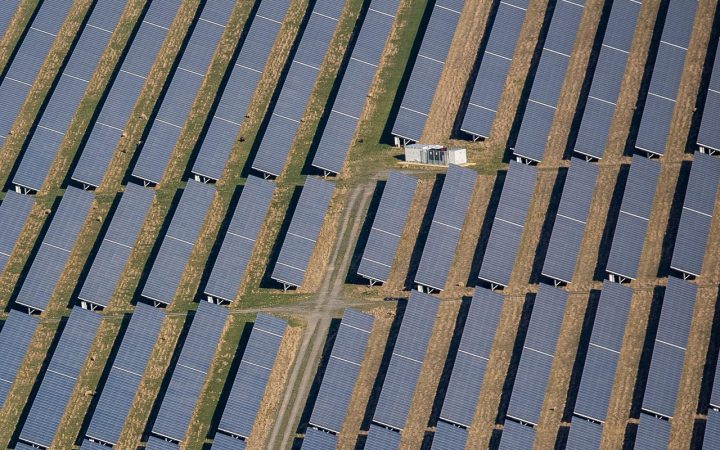 Rows of solar panels at a rural community solar farm installation under a bright morning sky.