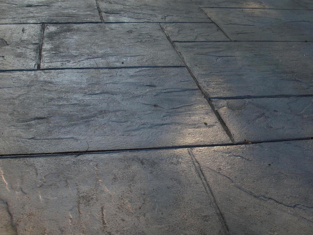 Construction workers pouring and smoothing a brand-new concrete patio slab.