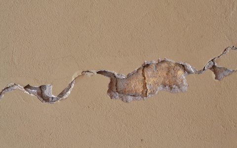A cracked and sunken concrete patio slab outside a residential home.