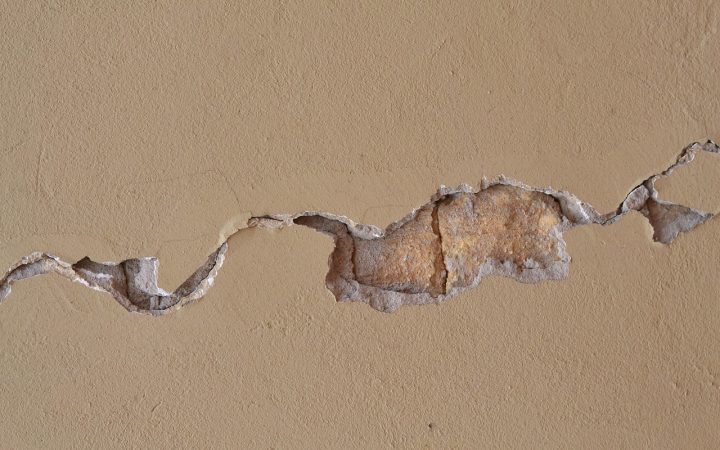 A cracked and sunken concrete patio slab outside a residential home.