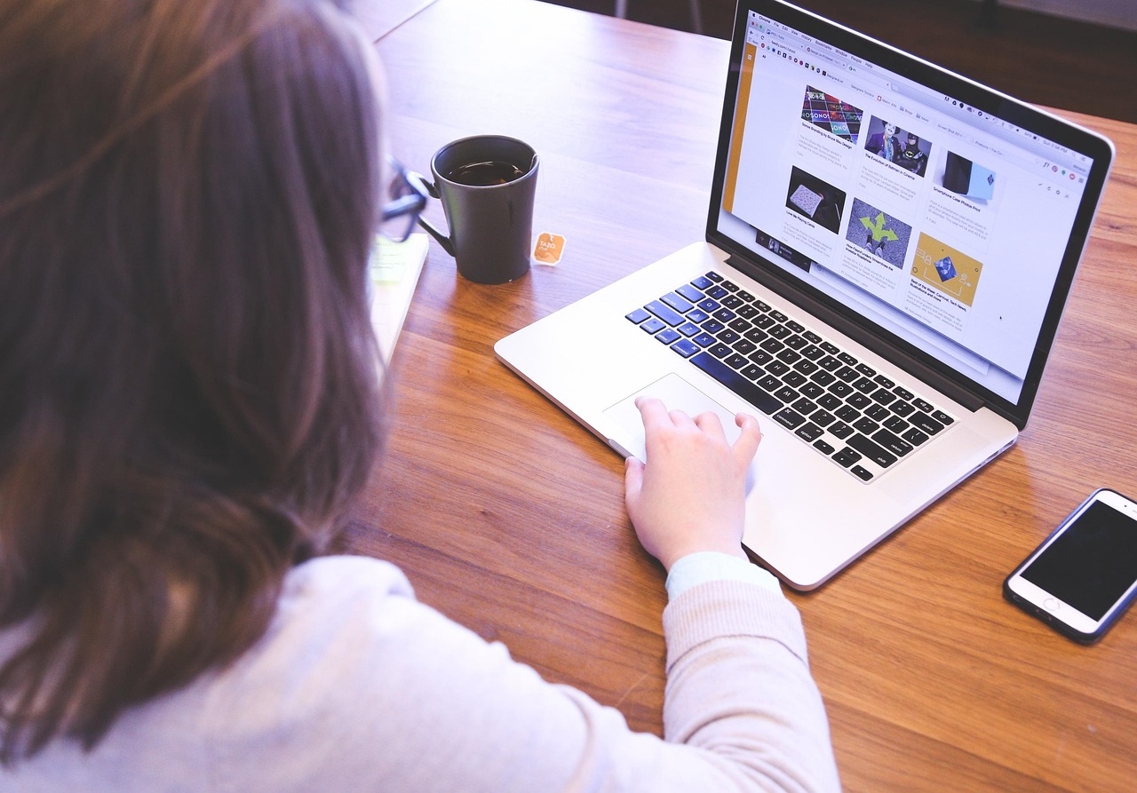 A corporate professional reading employee policy documentation on a laptop screen.