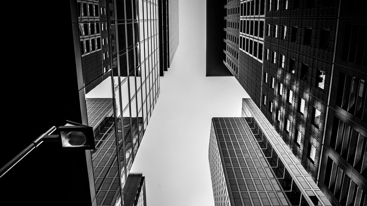 A corporate professional reflecting at a desk near a window overlooking a city skyline.