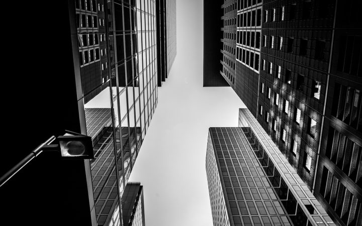 A corporate professional reflecting at a desk near a window overlooking a city skyline.
