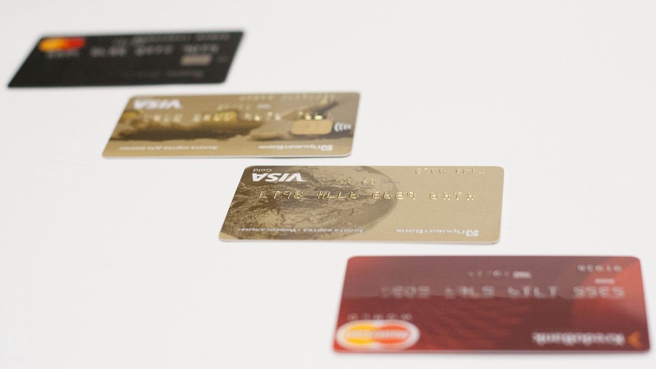 A modern credit card sitting next to a new smartphone and shopping receipts on a wooden desk.
