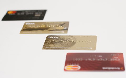 A modern credit card sitting next to a new smartphone and shopping receipts on a wooden desk.