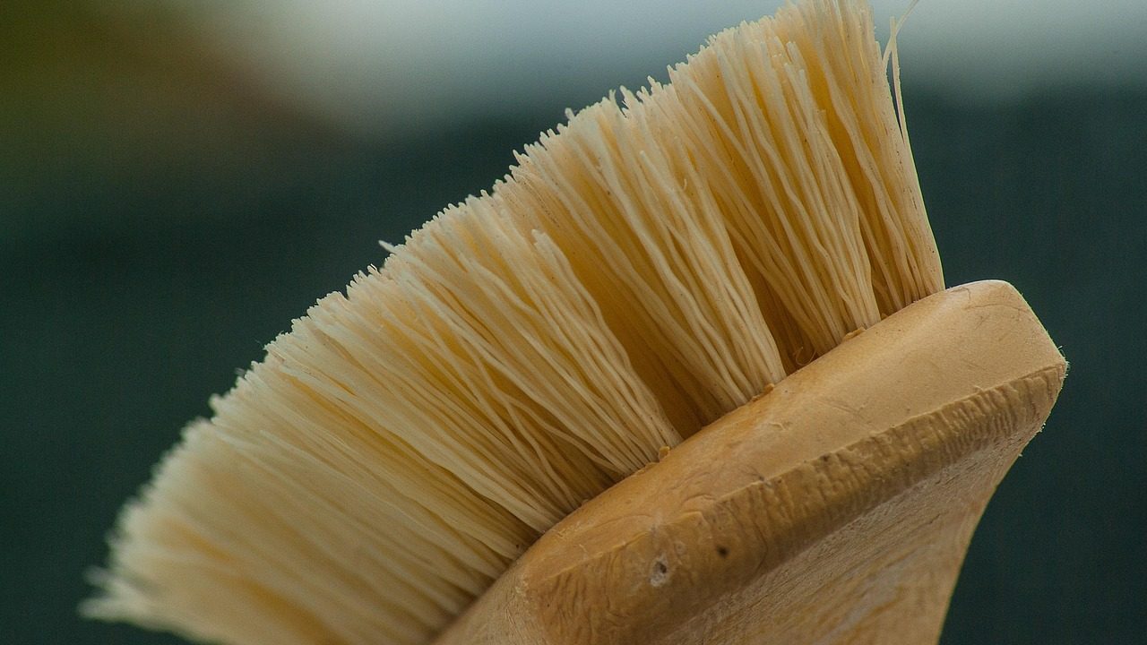 A flexible rotary dryer vent cleaning brush kit and detached metal dryer duct pipe in a home laundry room.
