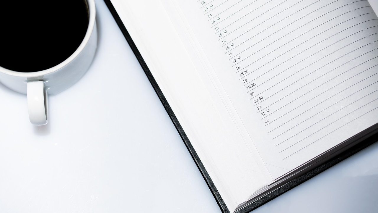 A high school course planning calendar and notebook neatly arranged on a wooden desk in a brightly lit office.
